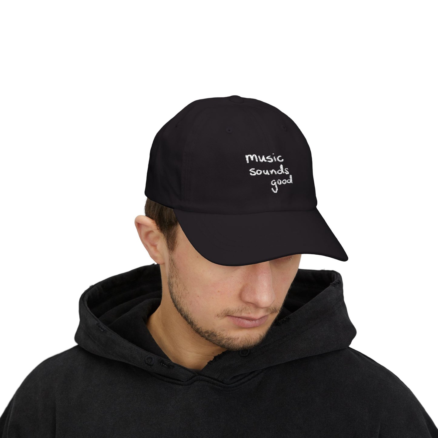 Person wearing a black cap with 'music sounds good' text on a white background