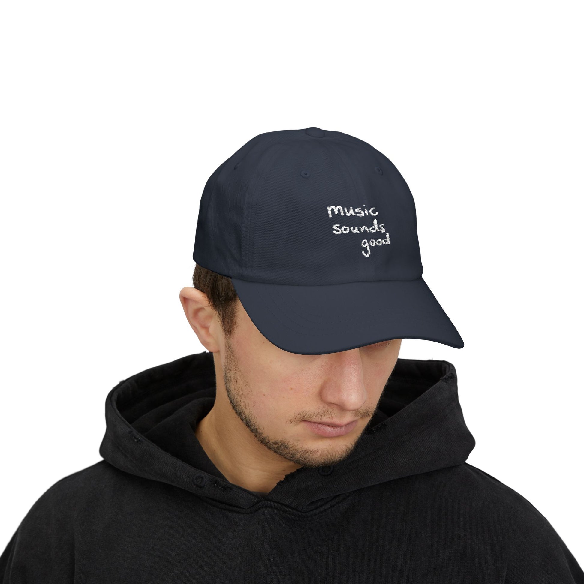 Person wearing a navy cap with 'music sounds good' text on a white background