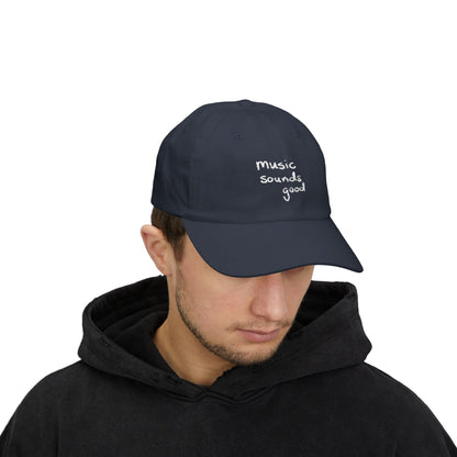 Person wearing a navy cap with 'music sounds good' text on a white background