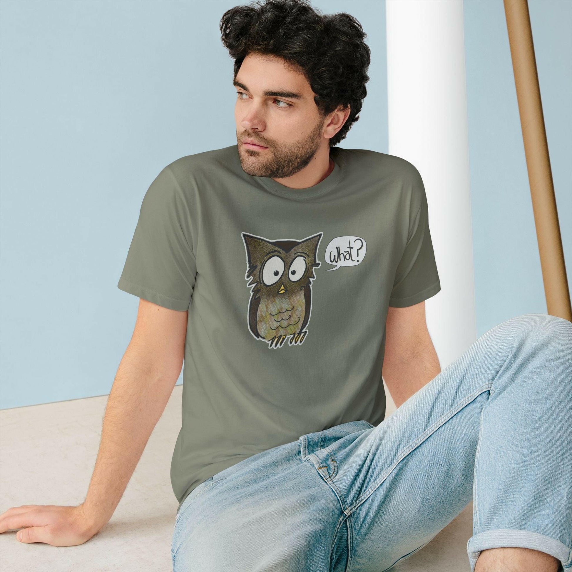 Man wearing a t-shirt with an owl graphic sitting on a floor.