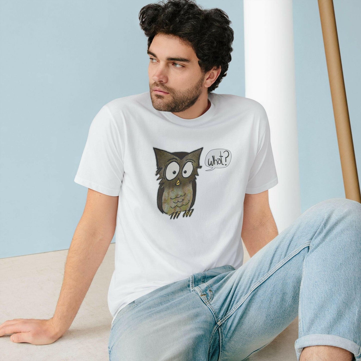 Man wearing a white t-shirt with an owl graphic sitting on a light blue background