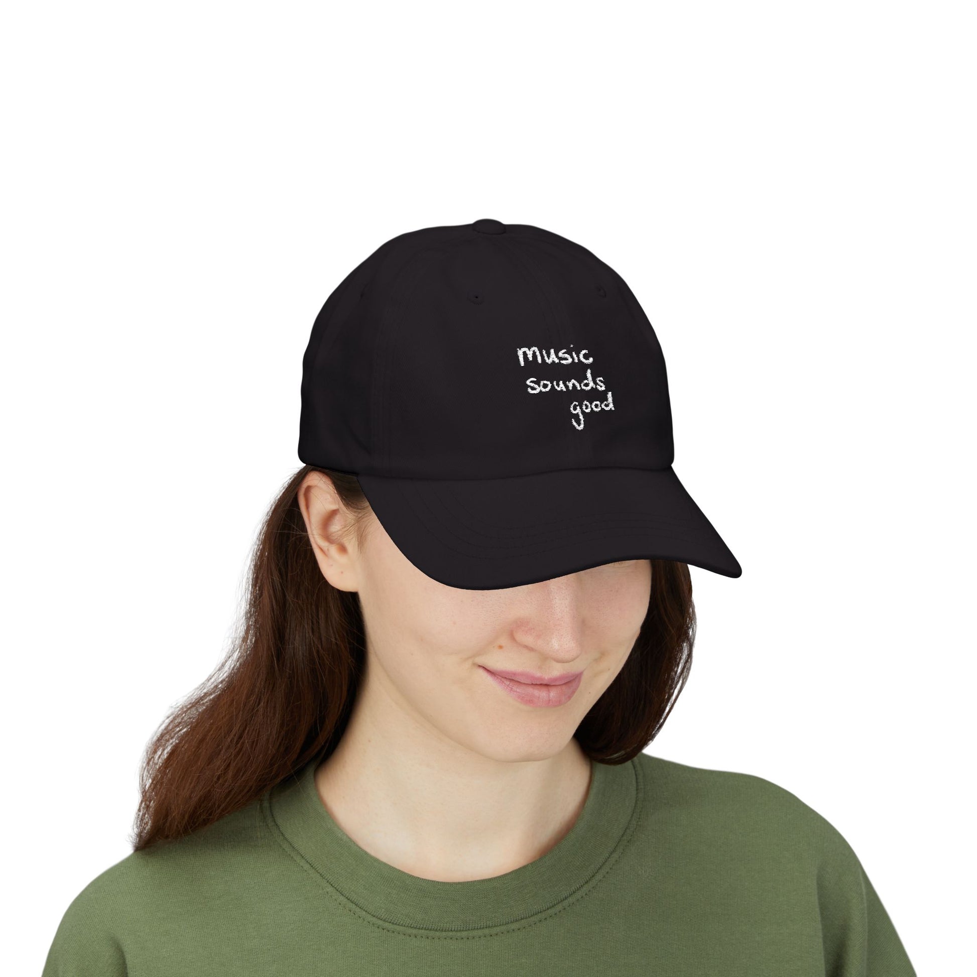 Woman wearing a black cap with 'music sounds good' text on a white background