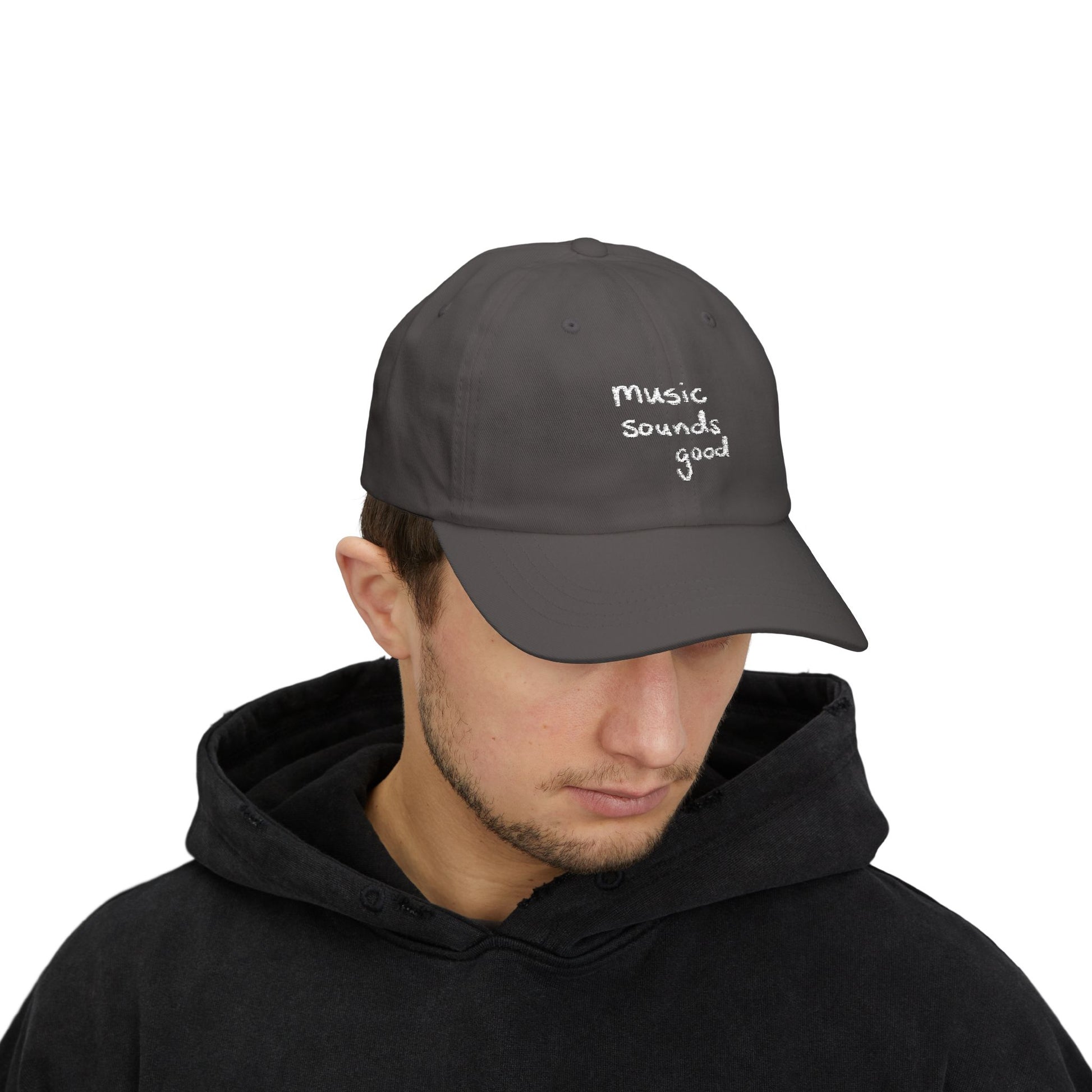 Person wearing a dark gray cap with 'music sounds good' text on a white background