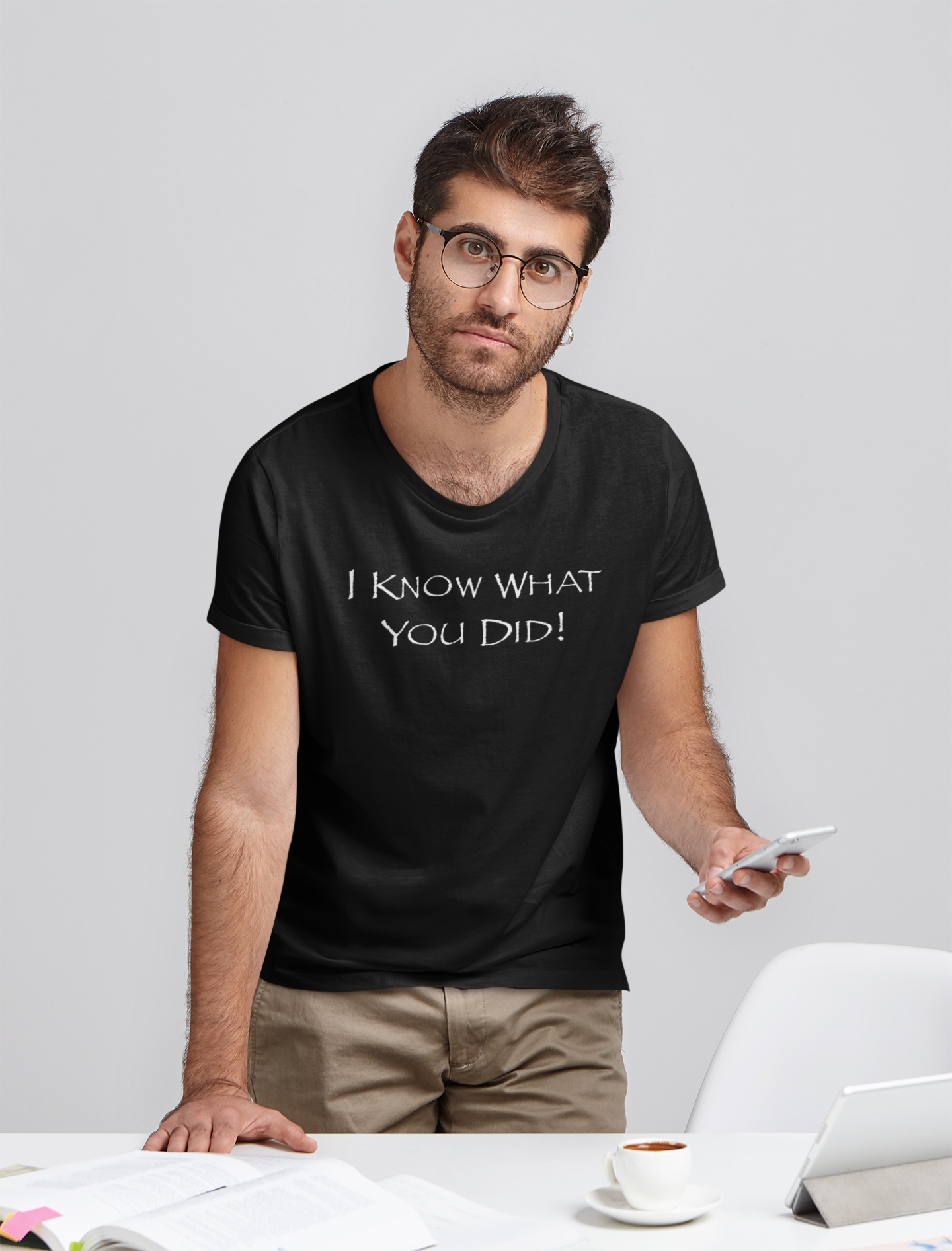 Man wearing a black t-shirt with text, standing in an office setting.