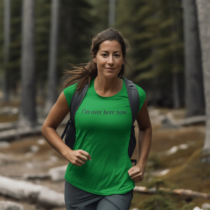 Woman in a green "I'm Over Here Now" T-shirt hiking in a forest