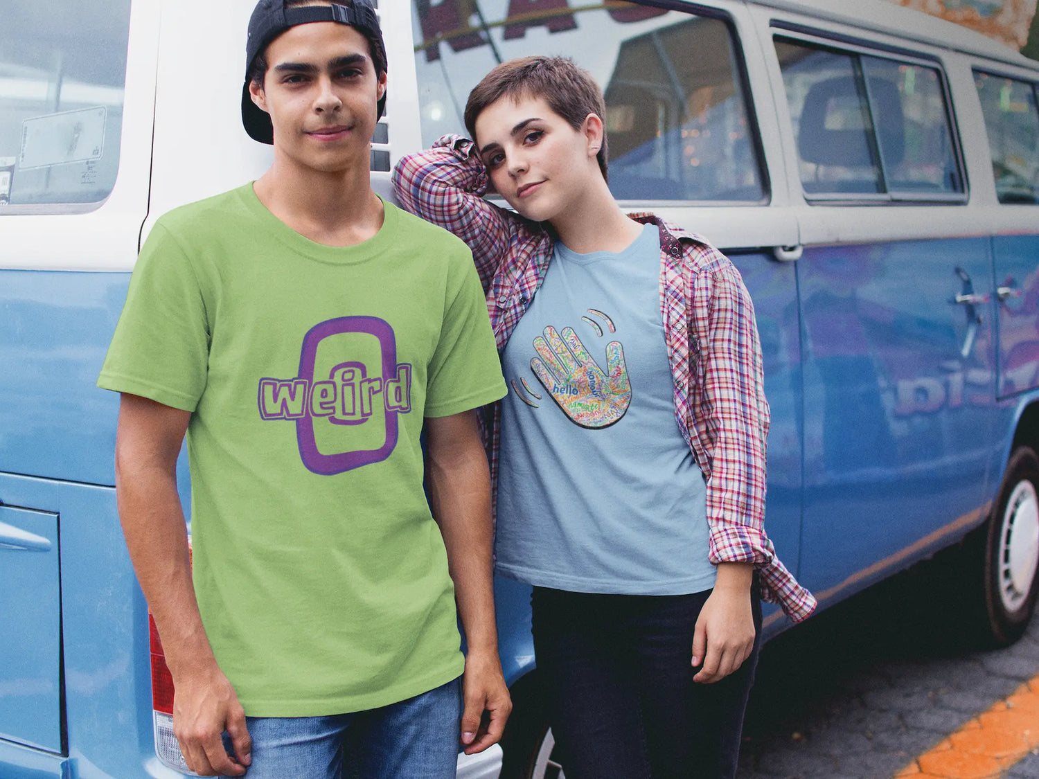 Two people standing in front of a blue van, one wearing a green 'weird' t-shirt and the other in a blue shirt with a handprint design.