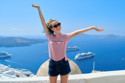 Woman with arms outstretched in front of a scenic view with boats and blue sky