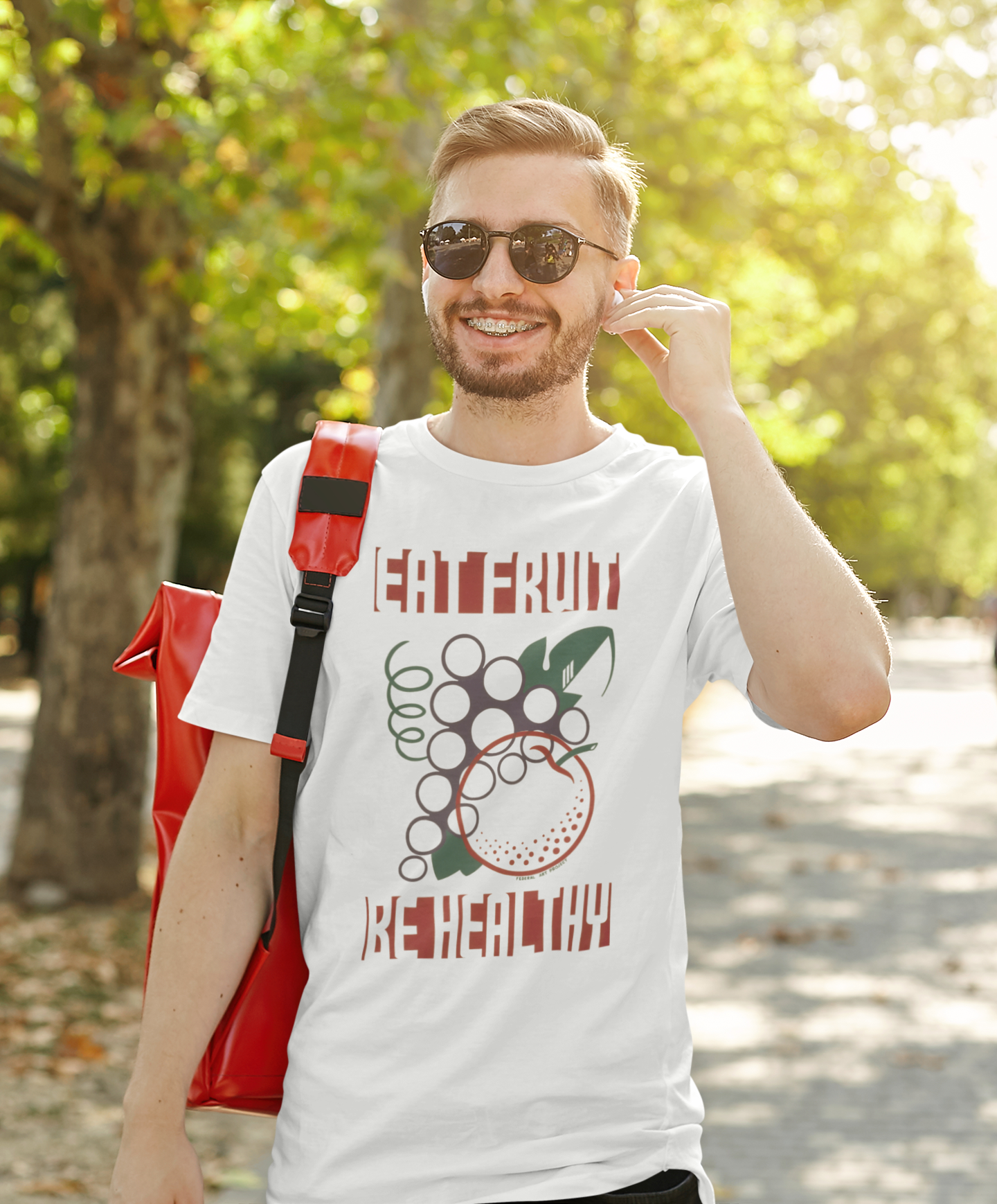 Man wearing a white t-shirt with a graphic design and the text "EAT FRUIT BE HEALTHY" outdoors