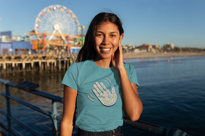 Woman wearing a teal T-shirt with a colorful hand graphic filled with greetings from many languages.